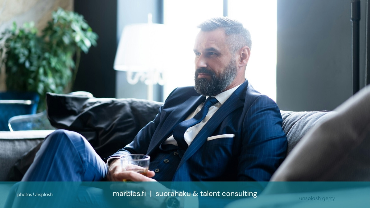 Haastateltava kandi istuu rauhallisesti tummalla sohvalla / Marbles